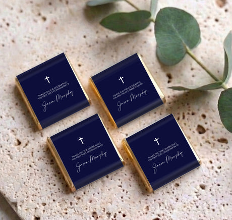 Four navy blue mini chocolate favors with white cross and personalised name on wrappers