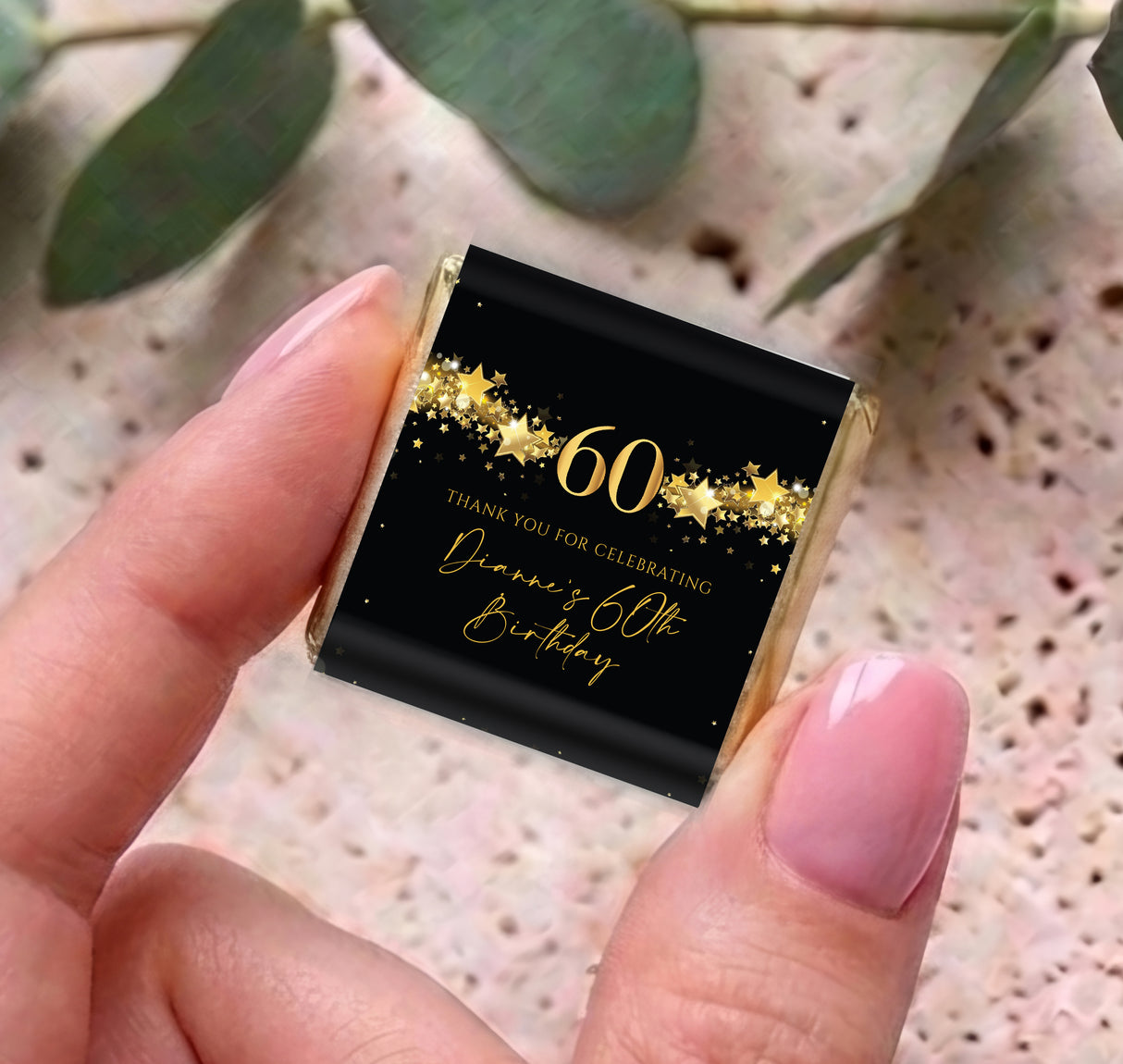 Handheld black mini chocolate box with gold stars and “Dianne’s 60th Birthday” text