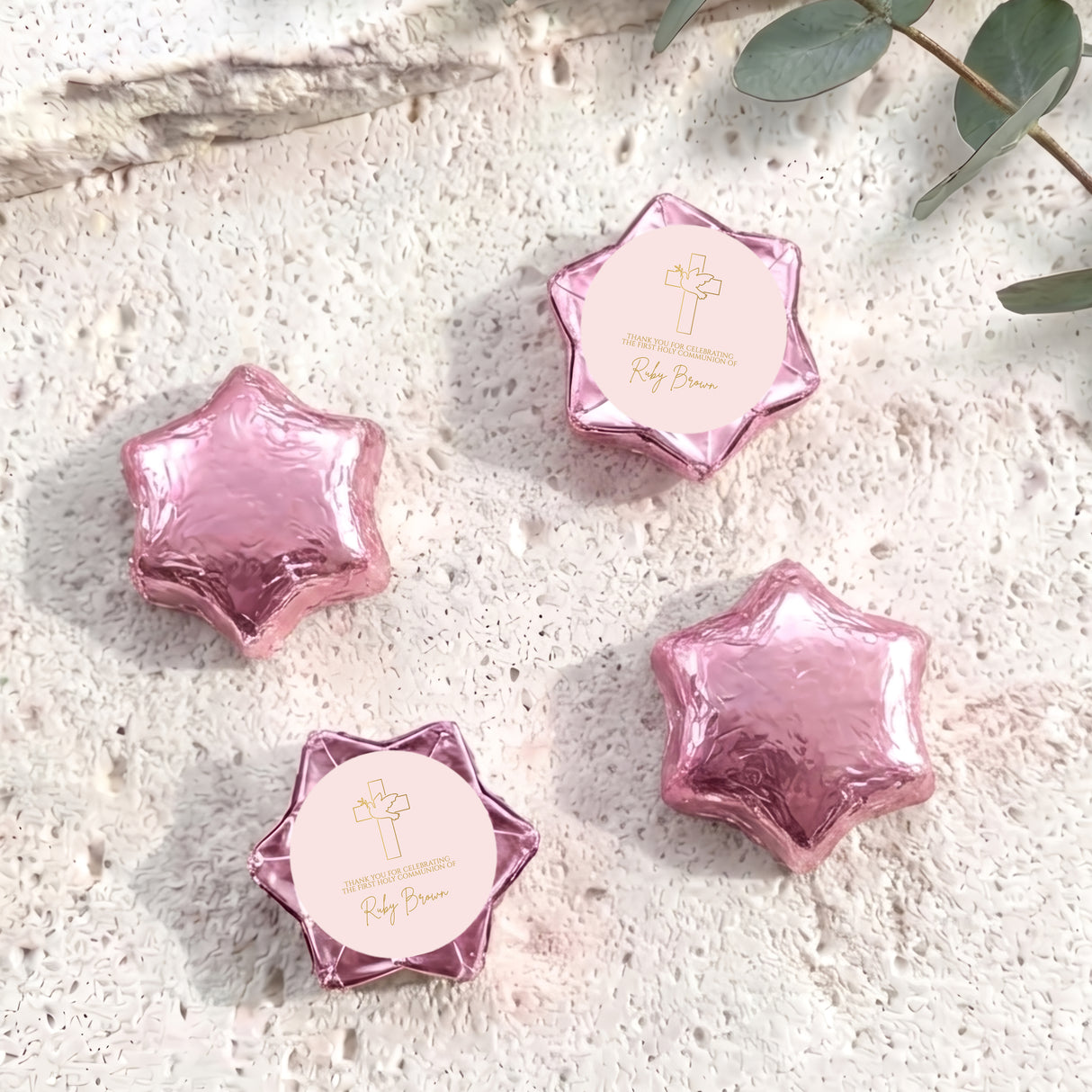Pink foil-covered chocolate stars with cross logo medallion