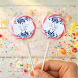 Personalised lollipops with blue floral labels and pastel pink trim, held in hand.