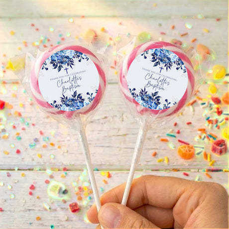 Personalised lollipops with blue floral labels and pastel pink trim, held in hand.