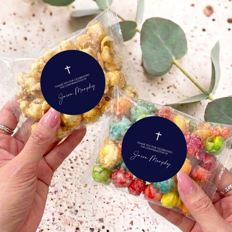 First Communion popcorn bag with navy label and white cross, held in hands