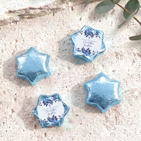 Star-shaped foil-covered chocolate pieces in light blue, with blue floral label