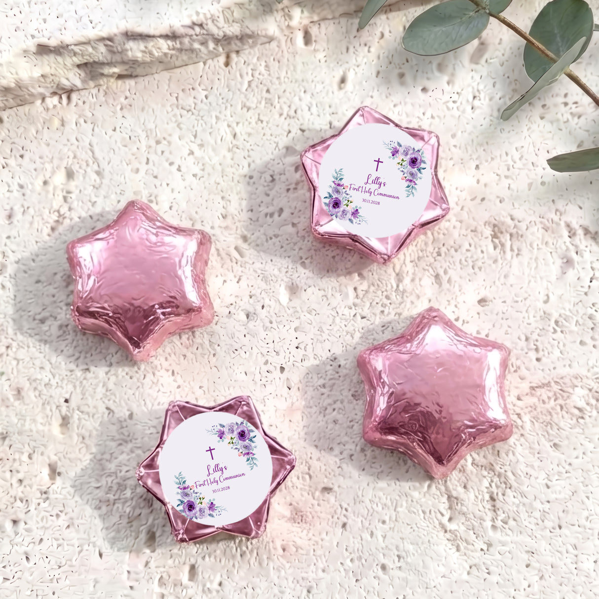 Foil-covered chocolate stars in pink with a First Holy Communion-style label