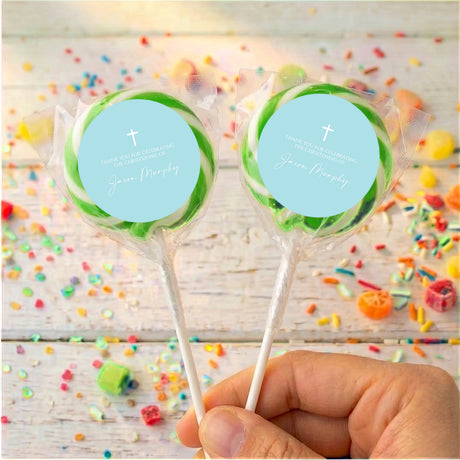Personalised christening lollipops with green-edged blue labels and white cross on sticks