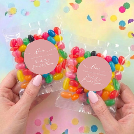 Two personalized jelly bean favor bags held in hands, clear wrappers with colorful beans