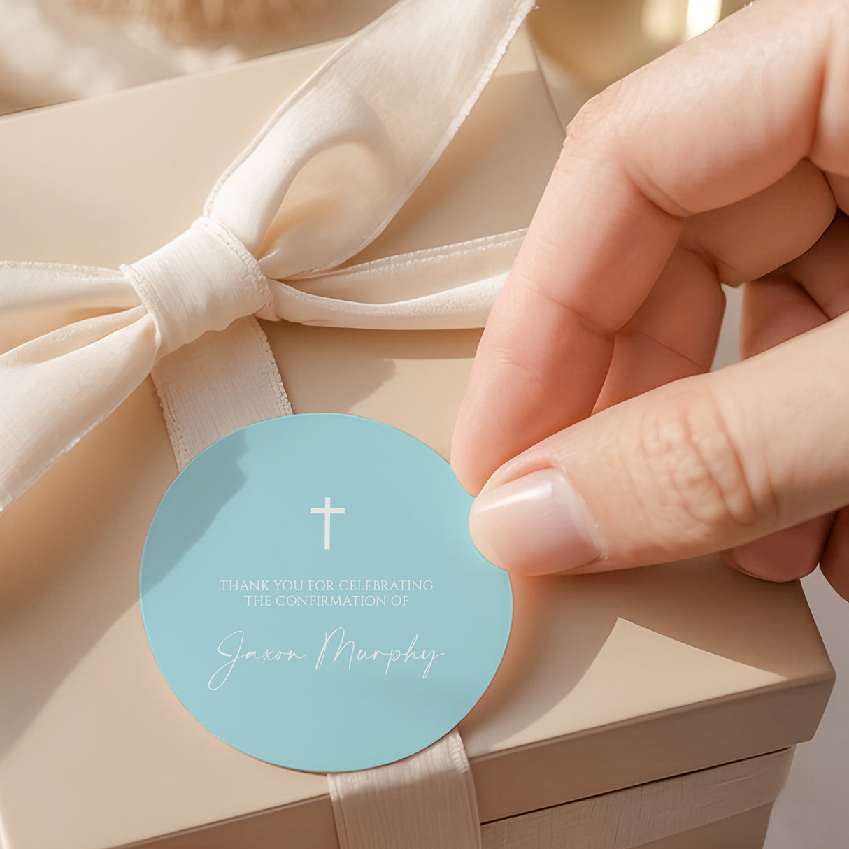 Pastel blue round confirmation label with white cross and text, held by hand
