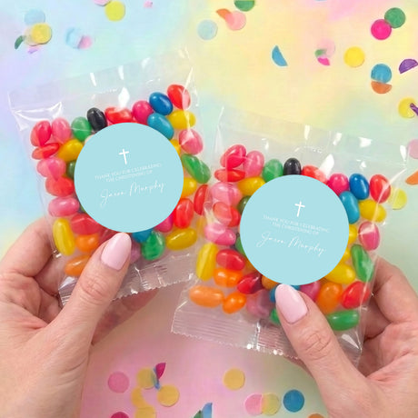 Two personalised jelly bean favor bags with pastel beans and blue cross labels