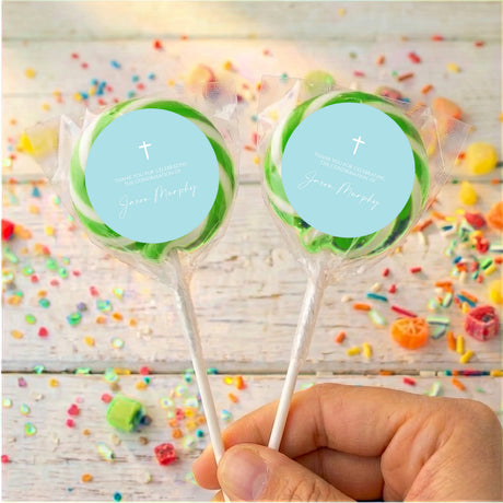 Two pastel blue confirmation lollipops with white cross labels, clear green-edged wrappers
