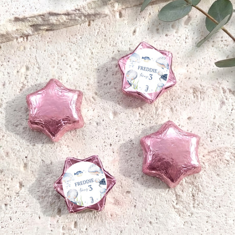 Pink foil-covered chocolate stars with personalised card reading “Freddie”