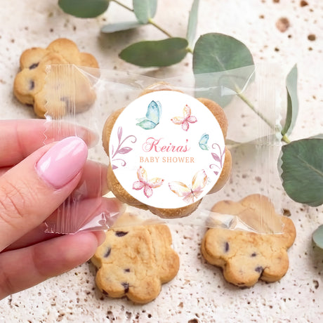 Cookie with round floral butterfly sticker for baby shower, held by fingers