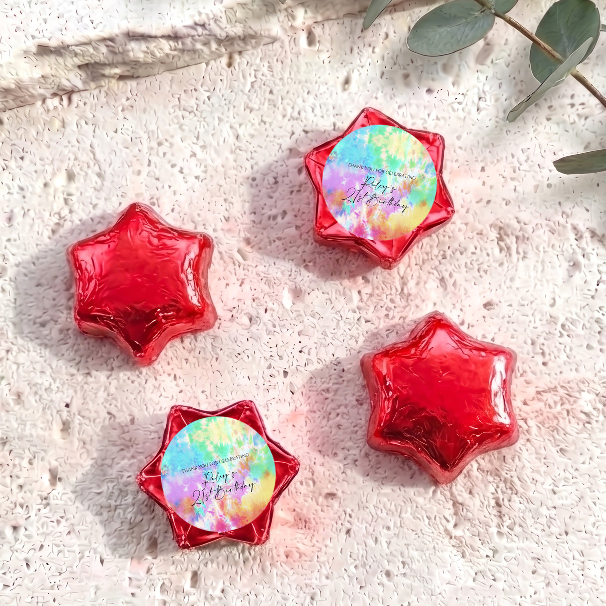 Foil-covered star chocolates in red with one pastel tie-dye foil star
