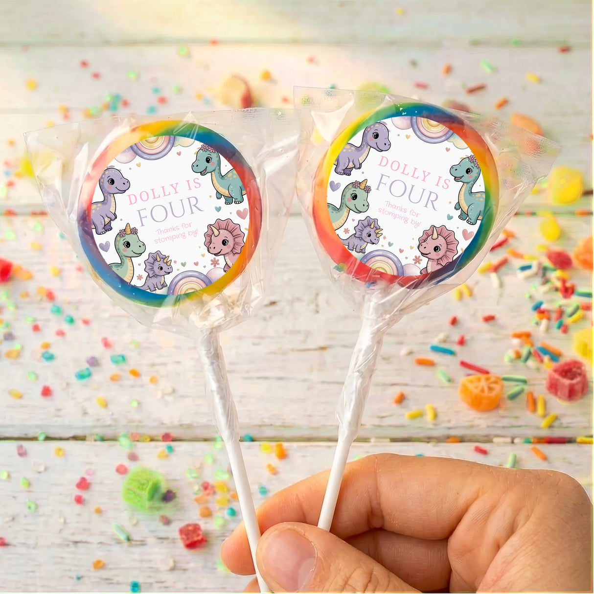 Rainbow-rim dinosaur birthday lollipops with round “Dolly is Four” wrapper labels
