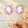 Pink-rim dinosaur birthday lollipops with round “Dolly is Four” wrapper labels