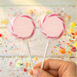Personalised cross lollipops with pink wrap, round personalised label, held in hand