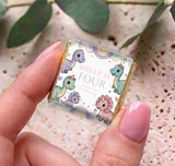 Hand holding personalized mini chocolate box, pastel dinosaur print and “Dolly is Four”