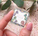 Close-up mini chocolate box wrapper with pastel dinosaurs and “Dolly is Four” text