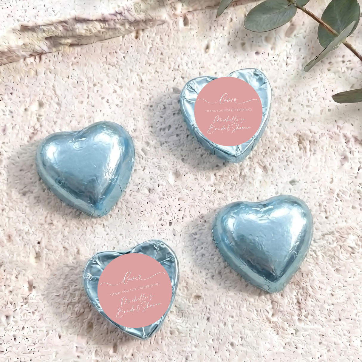 Light blue heart-shaped foil-covered chocolates with a round pink label on top