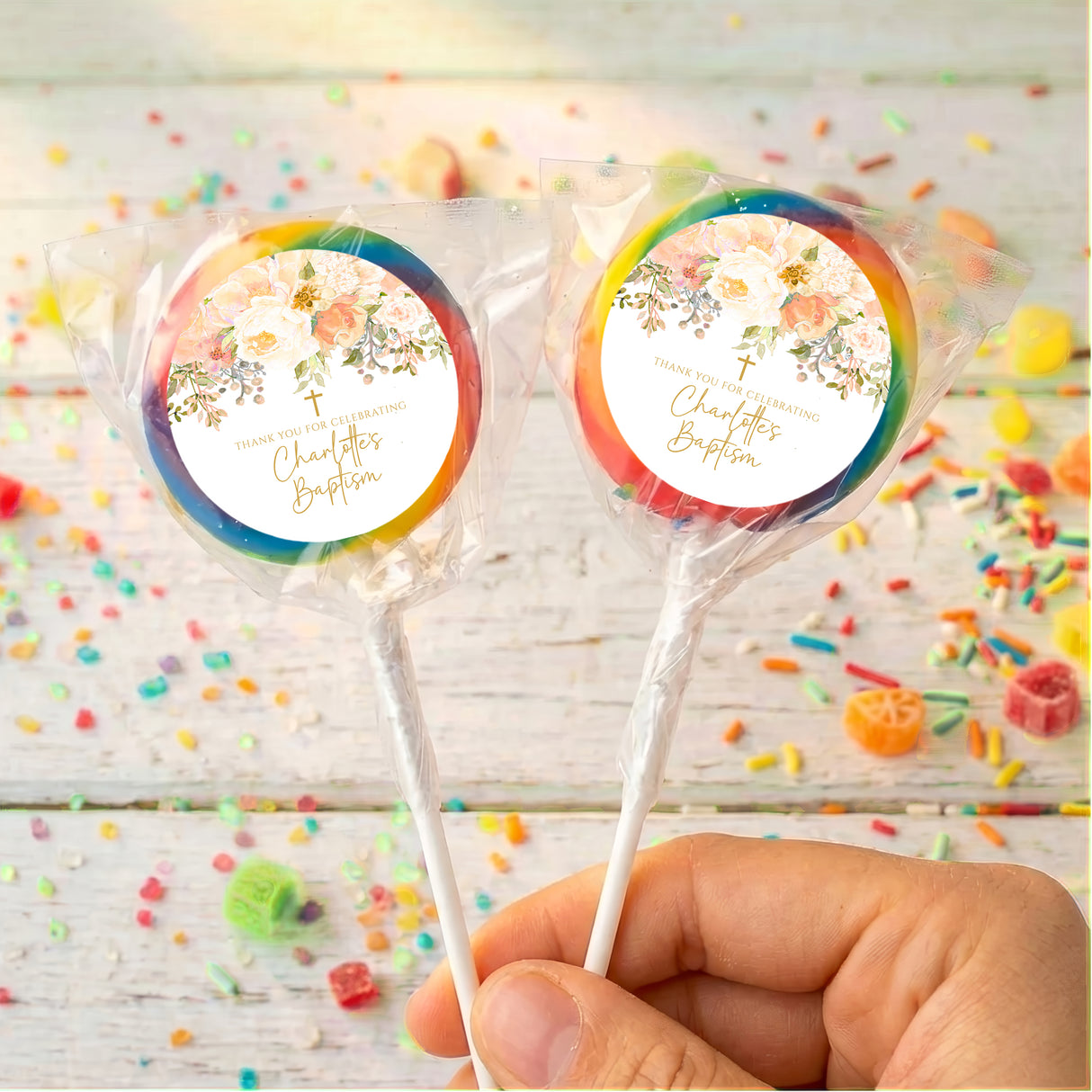 Personalised christening lollipops with blue and orange wrapped candy and floral labels