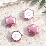 Foil-covered chocolate stars in pink wrap, each star with a white round love label.