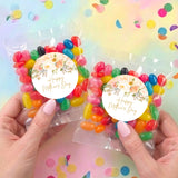 Two personalized Mother's Day jelly bean bags with floral round labels, held in hands
