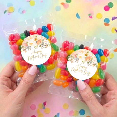 Two personalized Mother's Day jelly bean bags with floral round labels, held in hands