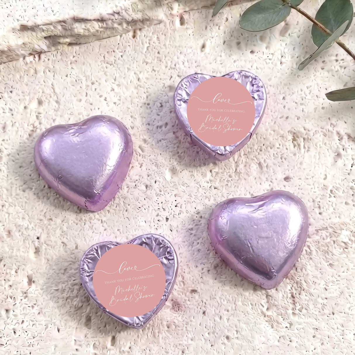 Purple heart-shaped foil-covered chocolates with a round pink label on top