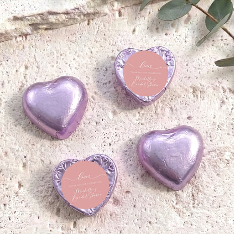 Purple heart-shaped foil-covered chocolates with a round pink label on top