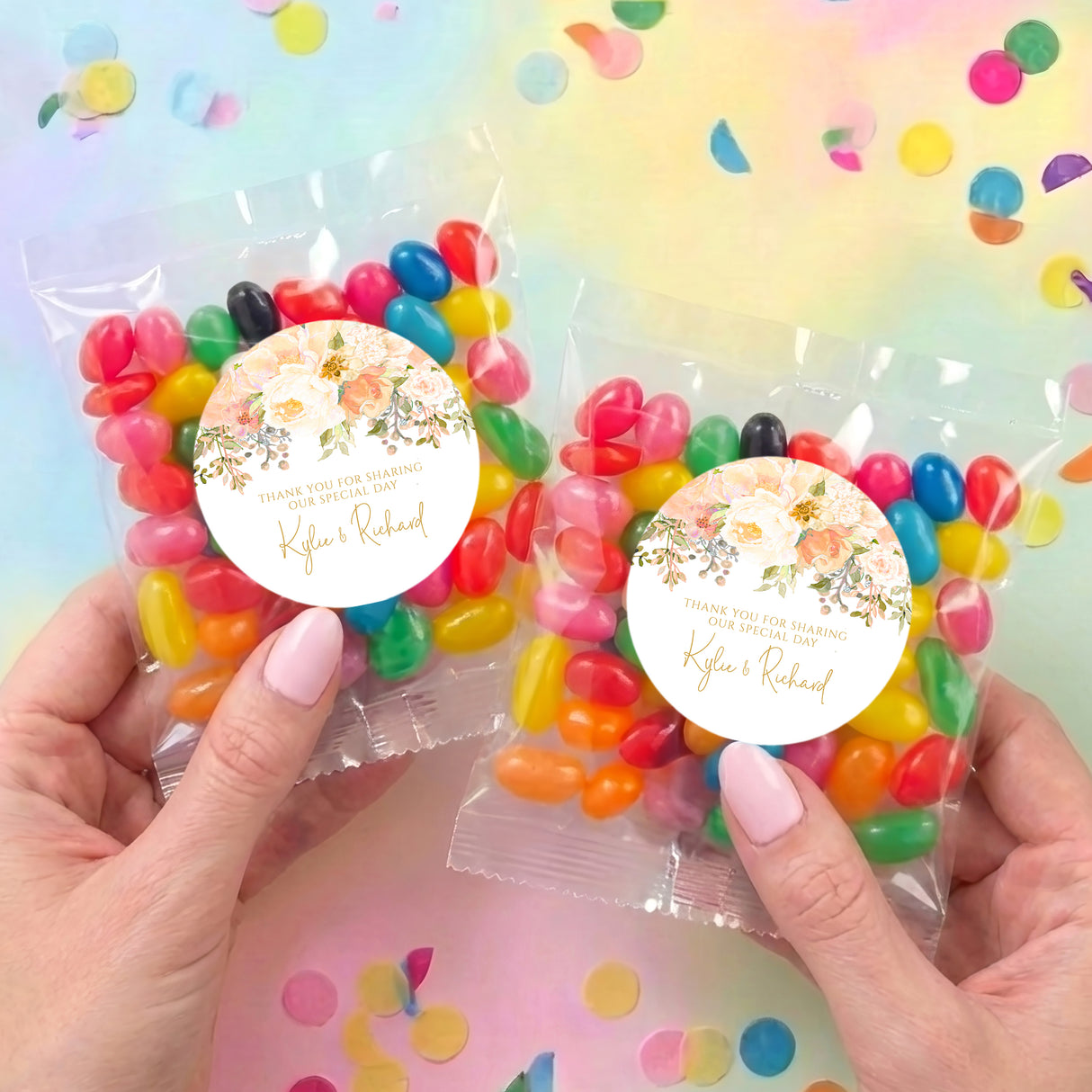 Two jelly bean bags with clear wrappers and round floral labels, multicolor candies, held