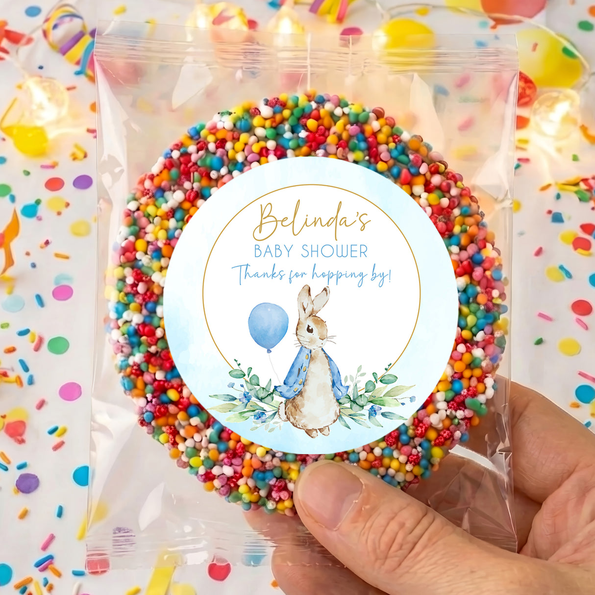 Clear bag of rainbow sprinkles with round baby shower label and rabbit illustration