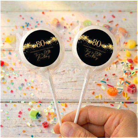 Two black 80th birthday lollipops with gold star “80” labels and personalized name
