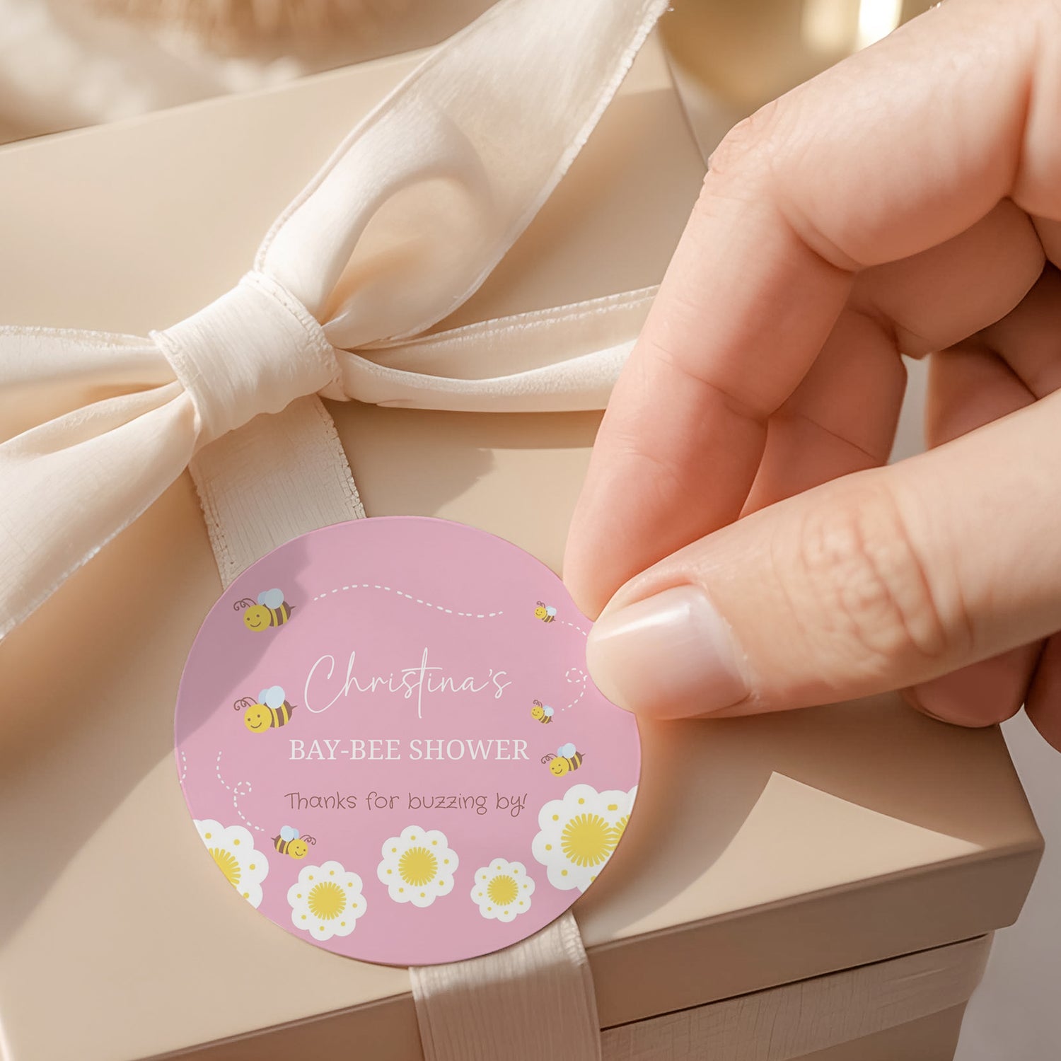 Pink round baby shower label with bee flowers and 'Thanks for buzzing by' wording
