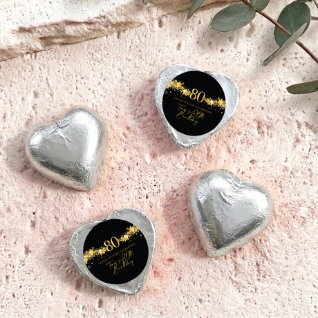 Silver foil-covered chocolate hearts with black 80th birthday label
