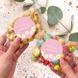 Pink popcorn bag with pink bee label for Bay-Bee Shower, held in hand