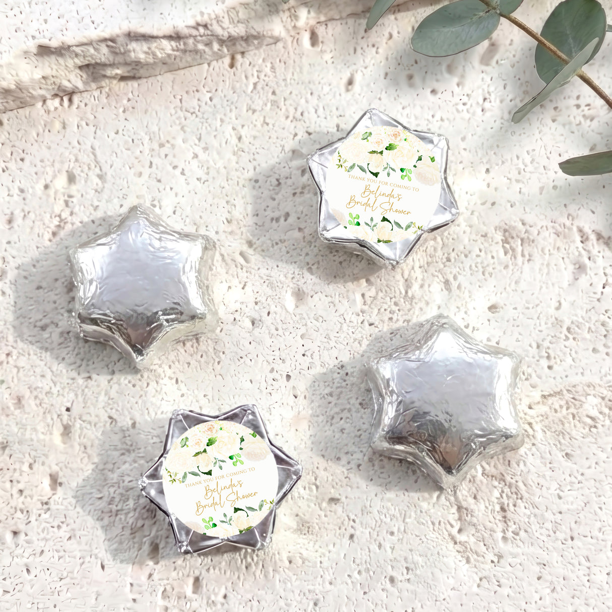 Foil-covered chocolate stars in silver with a printed floral label on one star.