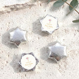 Silver foil-covered chocolate stars with white label featuring cross and floral design