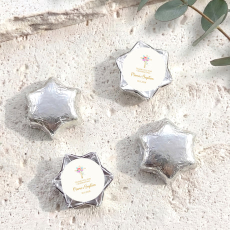 Silver foil-covered chocolate stars with white label featuring cross and floral design