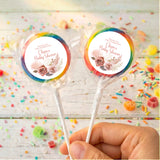 Personalised baby shower lollipops with rainbow floral round labels, held in hand