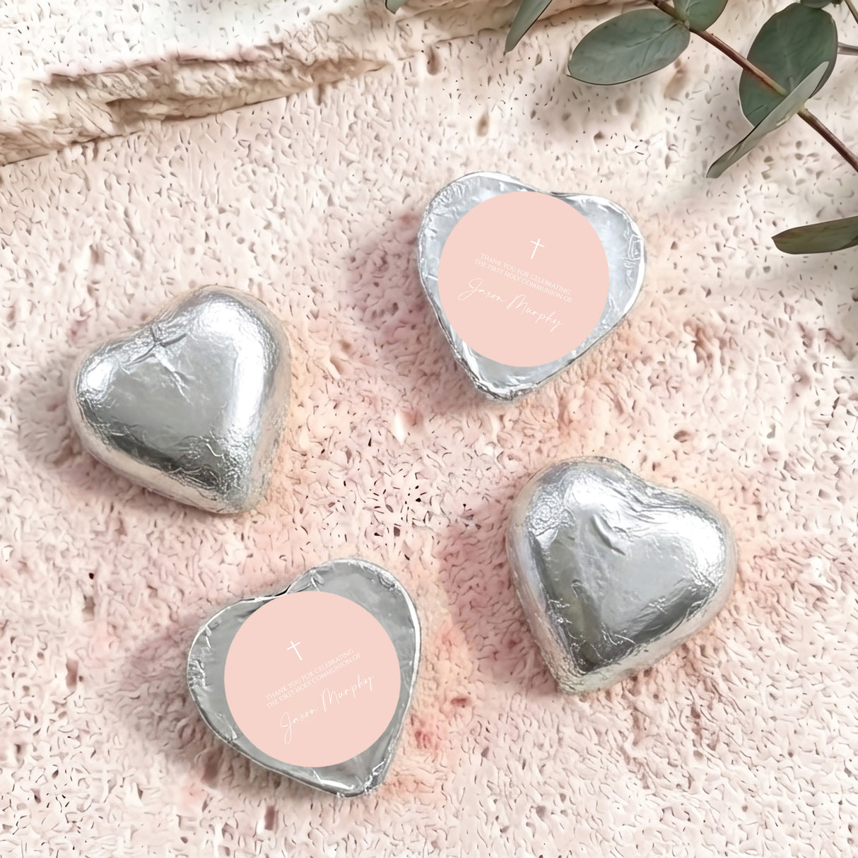 Silver foil heart chocolates with cross and personalised text on pale label.