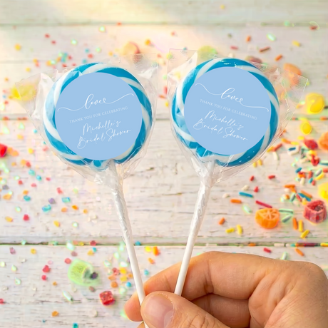 Bridal shower lollipops with blue personalized labels and teal blue candy swirls, held by hand
