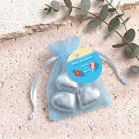 Icy blue metallic heart-shaped treat in clear organza drawstring bag with blue round tag