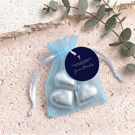 Light blue organza christening bag with navy round tag and cross charm