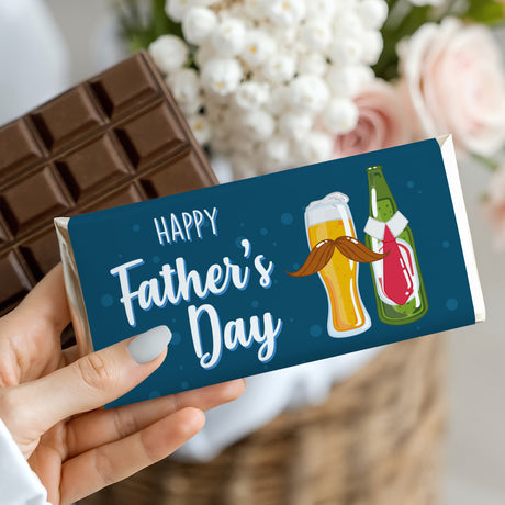 Hand holding Father's Day chocolate bar with blue wrapper, 'Happy Father's Day' and beer bottles