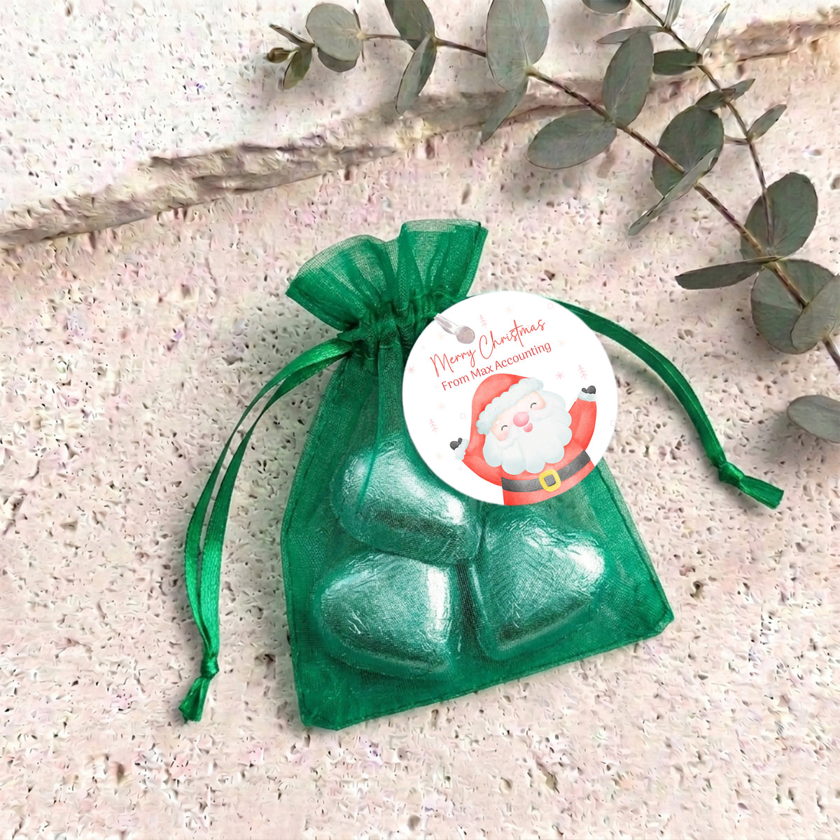 Organza gift bag with green heart-shaped chocolates and green pull-tie ribbon