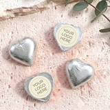 Foil-covered silver chocolate hearts with round personalized logo label