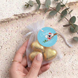 Gold heart chocolates in sheer white organza drawstring gift bag, held by hand with label
