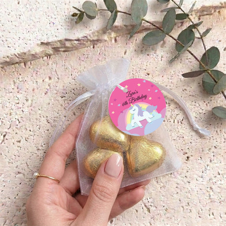 Gold heart chocolates in a pink organza gift bag with birthday tag, held