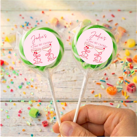 Pair of personalised martini lollipops with green-bordered pink labels and red text