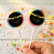 100th birthday lollipops with black round gold star labels, blue rim, held in hand