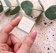 Hand holding a mini chocolate square with white custom message card and gold foil sides